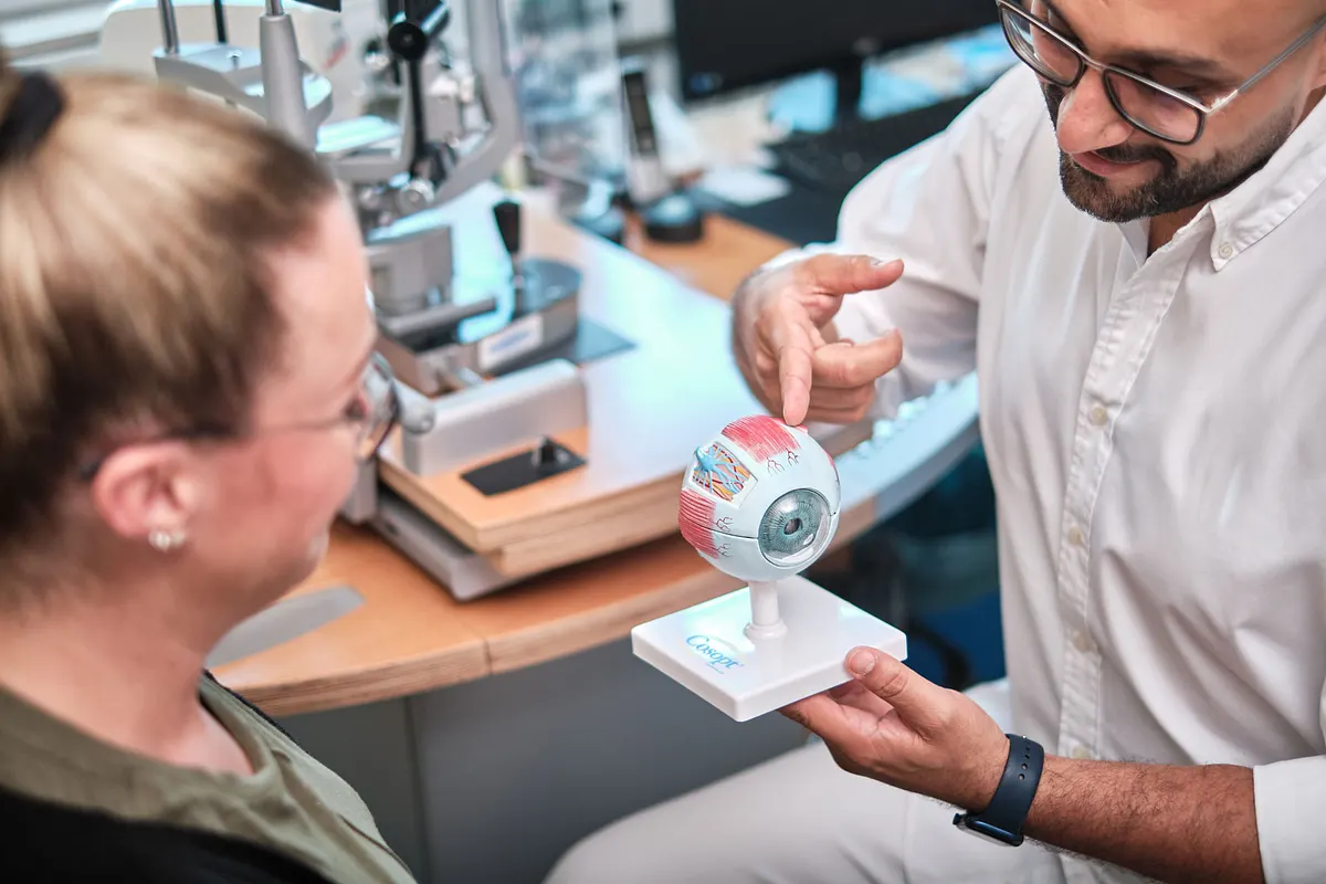 Arzt erklärt einer Patientin ein Augenmodell